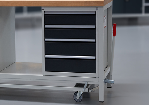 Nahaufnahme einer Werkbank auf Rollen mit einem Unterbauschrank mit fünf schwarzen Schubladen und einem seitlichen Hebel zur Höhenverstellung.